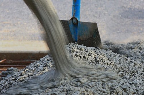 Fresh concrete being poured and spread with a shovel